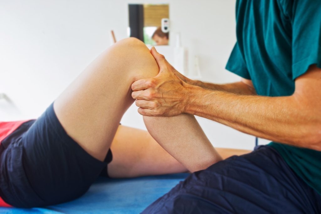 Physical therapist testing patient's knee mobility