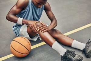 Basketball player holding knee on basketball court
